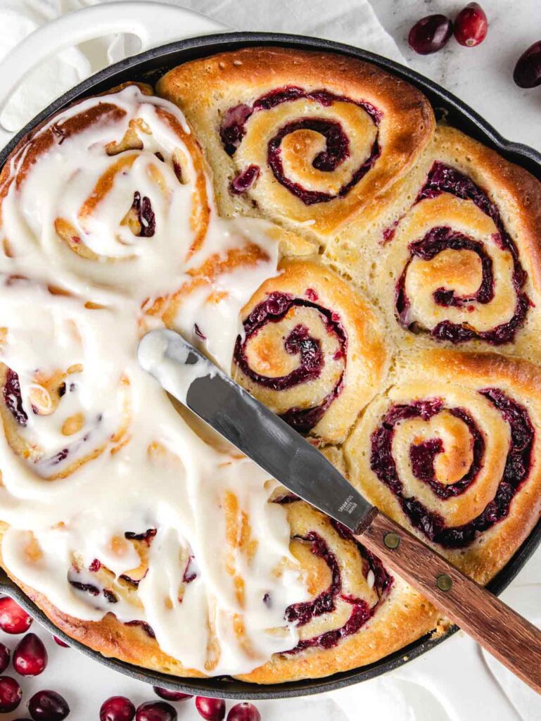 Cranberry rolls being iced.
