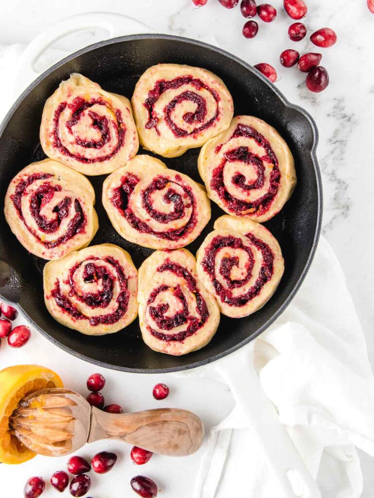 Unproofed rolls with cranberry jam in cast iron pan.