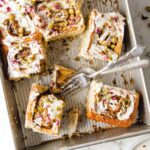 Half-eaten sheet pan of pistachio swirls with 2 forks.