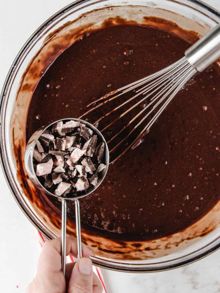 Adding spoonful of candy to chocolate cake batter.
