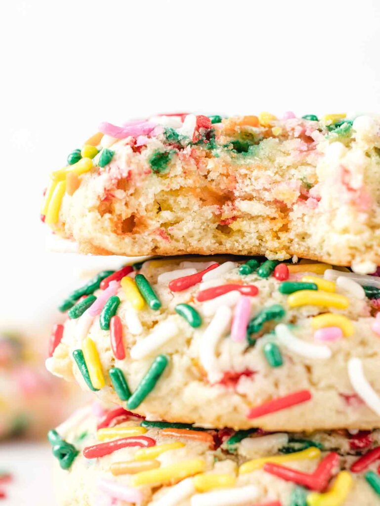 Close up of stack of cookies with sprinkles with bite missing.