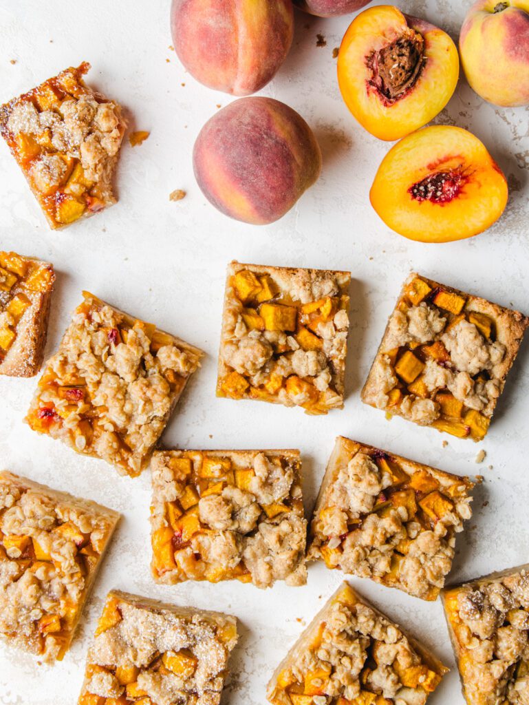 Cookie squares on board with whole and sliced peaches.