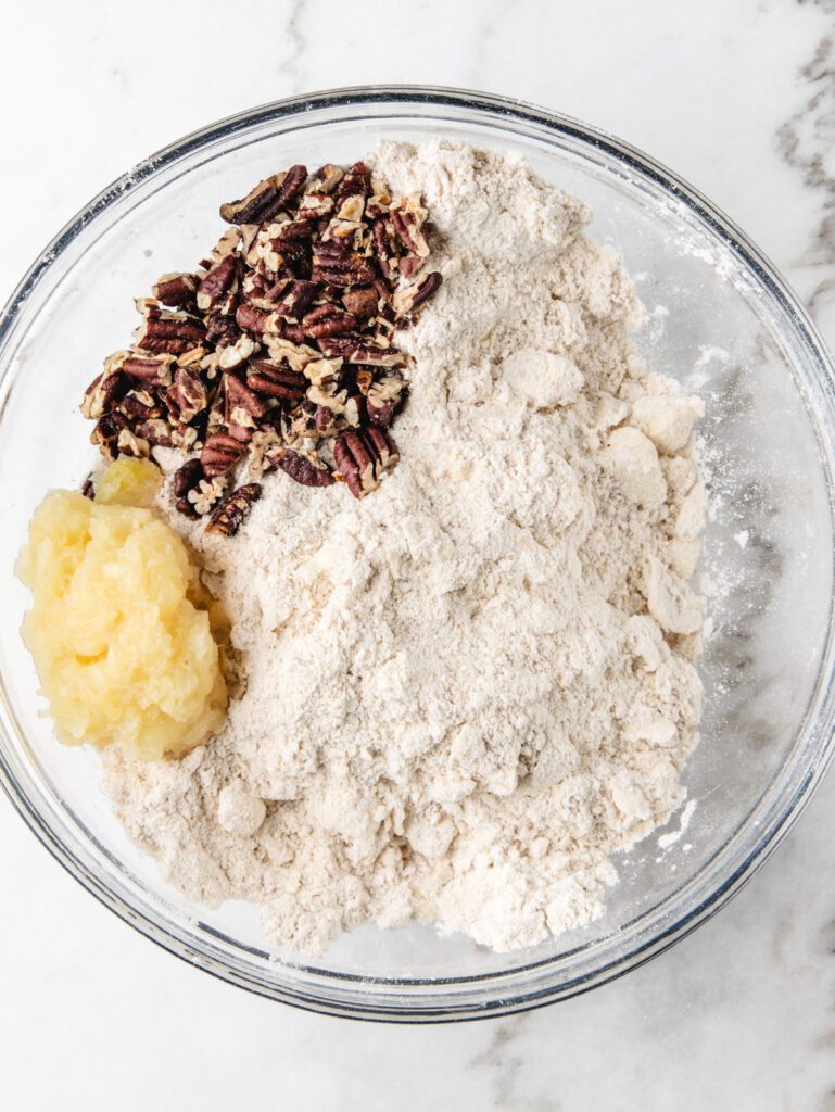 Crushed pineapple and pecans in bowl of flour.