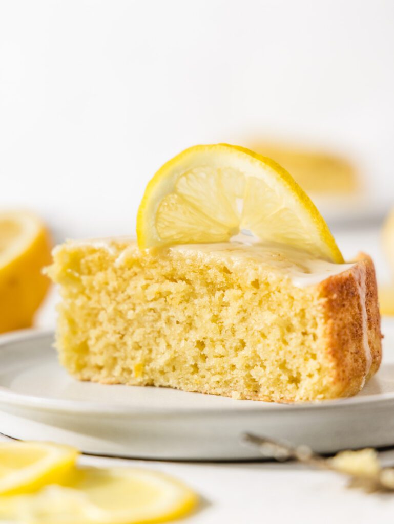 Side of cake slice on plates with lemon slice on top.