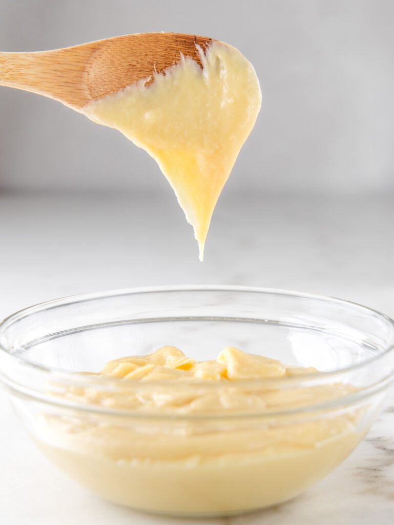 Choux dough falling off wooden spoon.