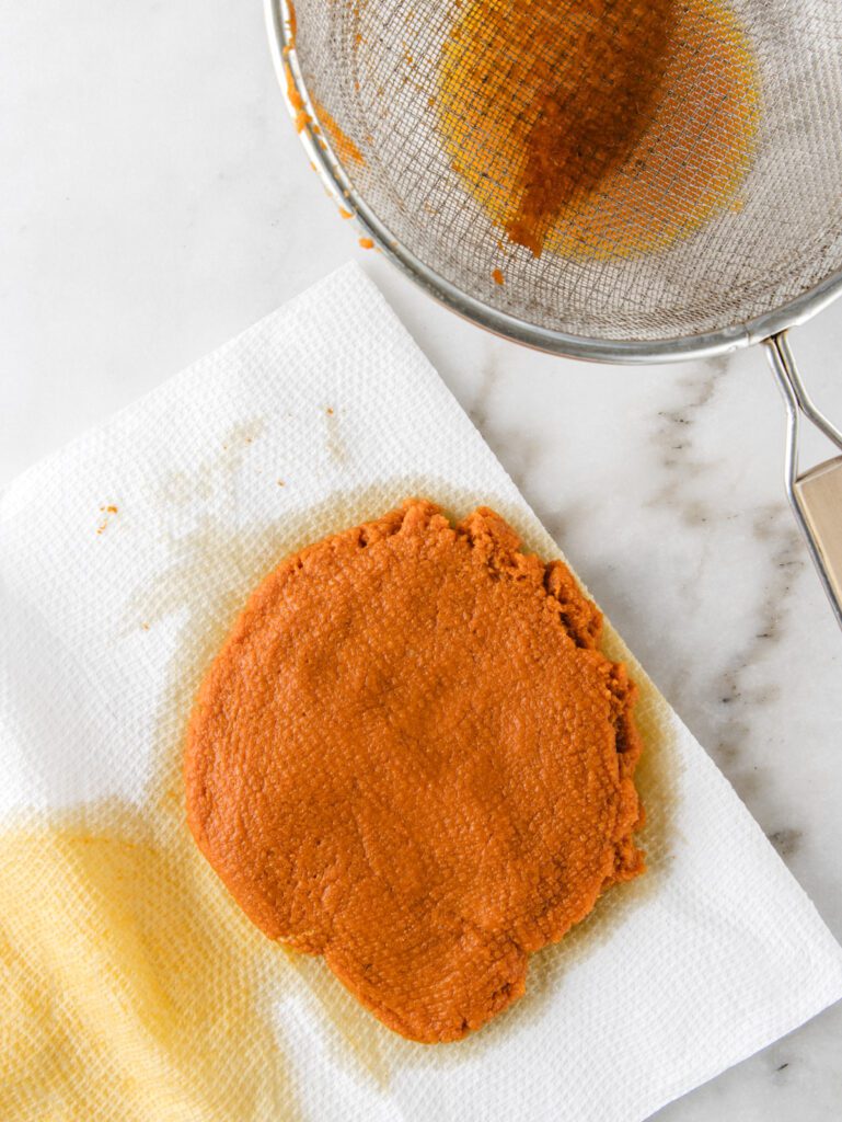 Strainer next to pumpkin puree on paper towels.