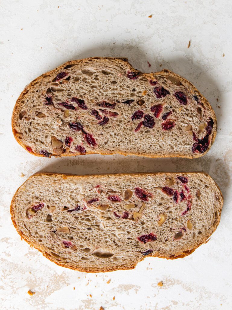 Two slices of bread on bread with cranberries and walnuts. 