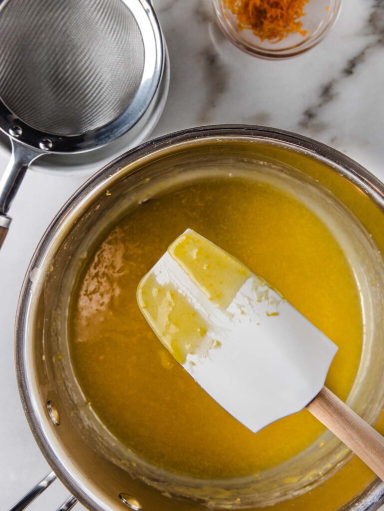 Spatula over pan of orange curd.