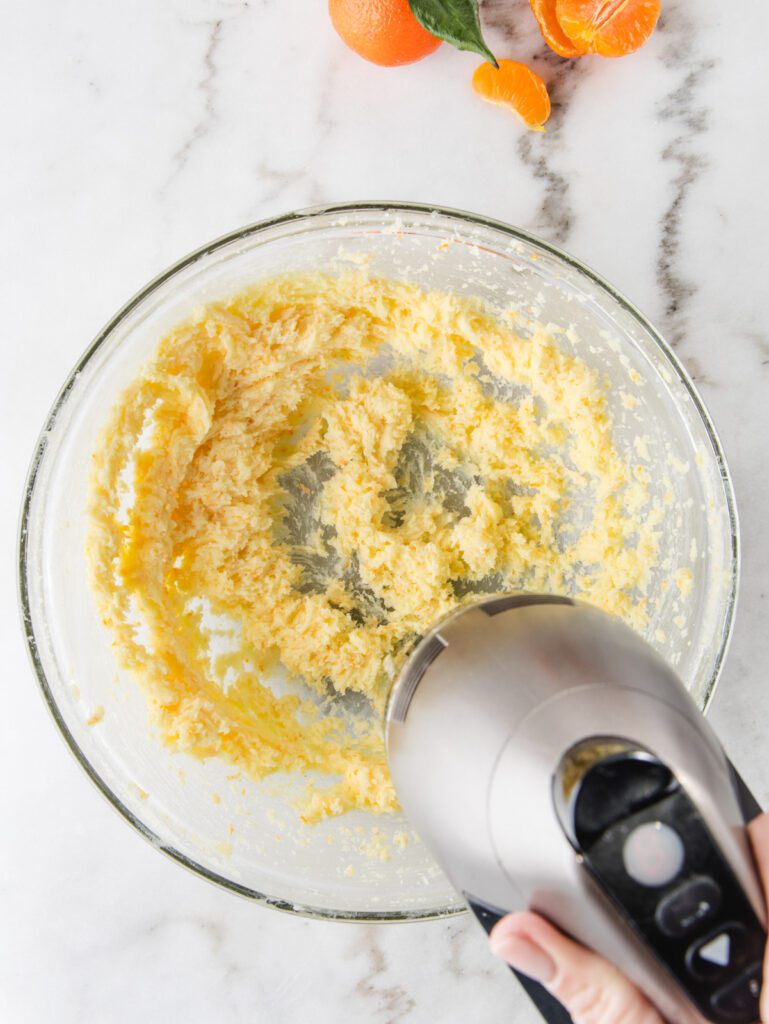 Whipping butter in glass bowl with hand mixer.