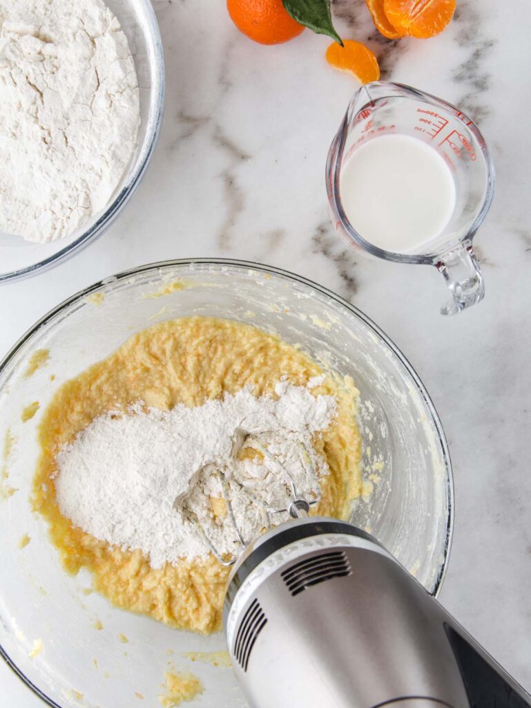 Mixing flour into cake batter with hand mixer.