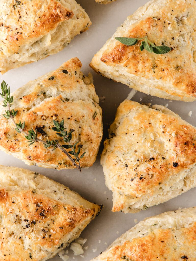 Scones lined up on board with fresh herbs.