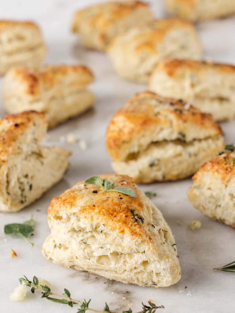 Scones scattered on table with fresh herbs.