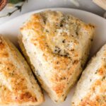 Scones on marble board with cheese and pepper on top.