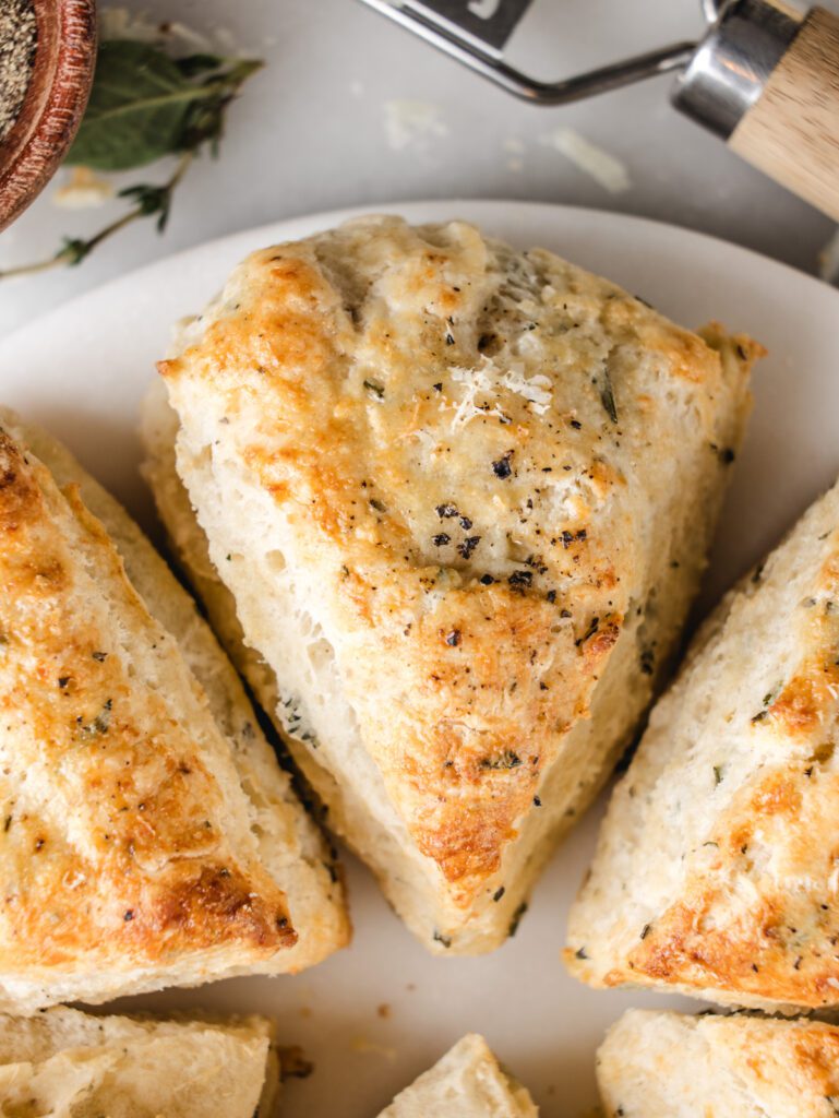 Scones on marble board with cheese and pepper on top.