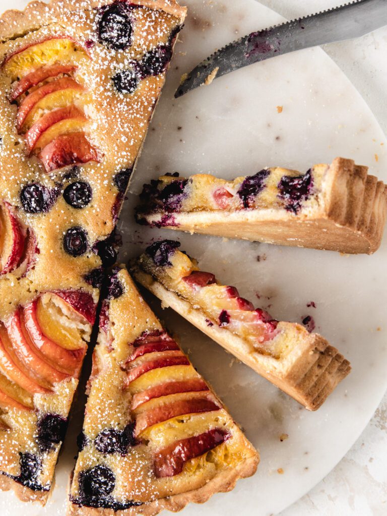 Sliced peach tart with two slices on side.