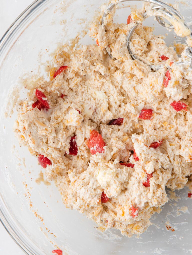 Biscuit dough in bowl with pimentos and cheese.
