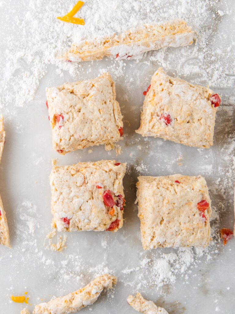 Sliced biscuit dough on floured marble.