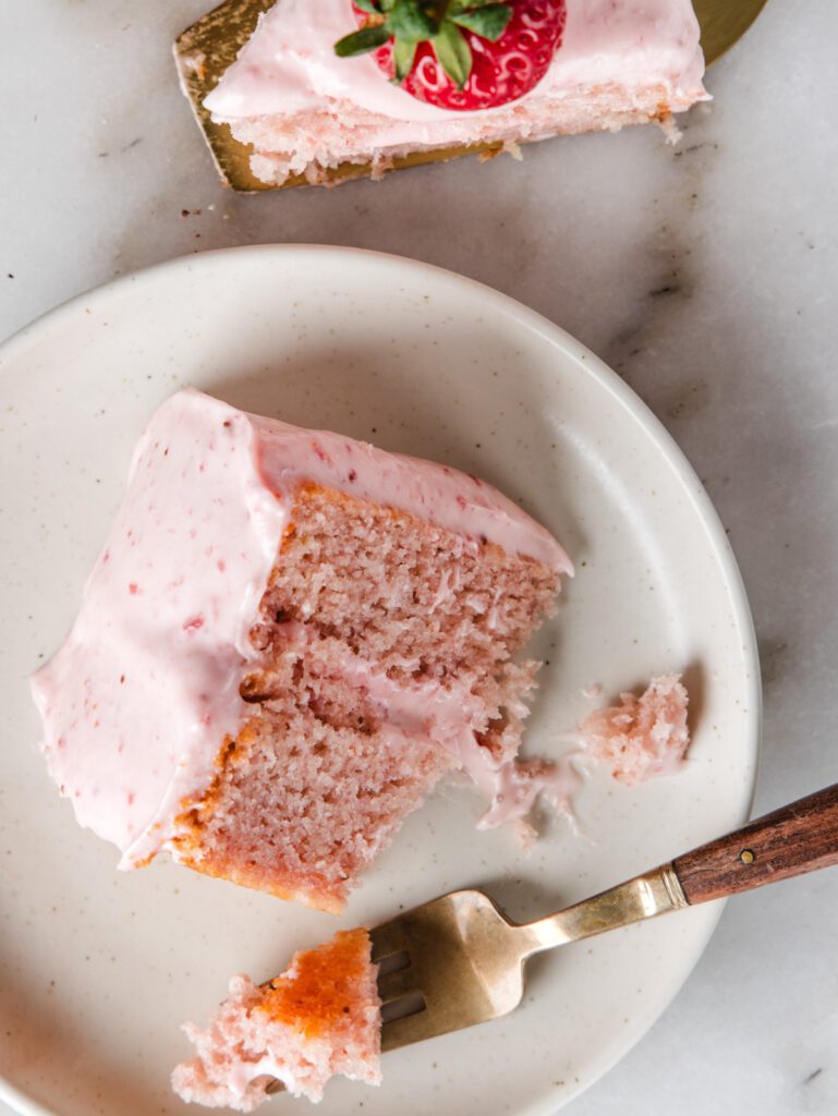Slices of strawberry cake on plate with a fork and on cake server.
