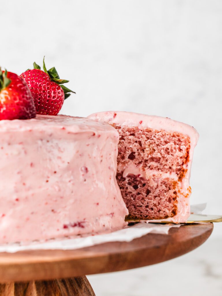 Removing slice of strawberry cake from cake plate.