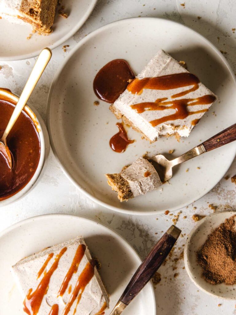 Pieces of cheesecake with caramel on top scattered on dishes.