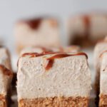 Sideview of sliced cheesecake with caramel drizzle on top.