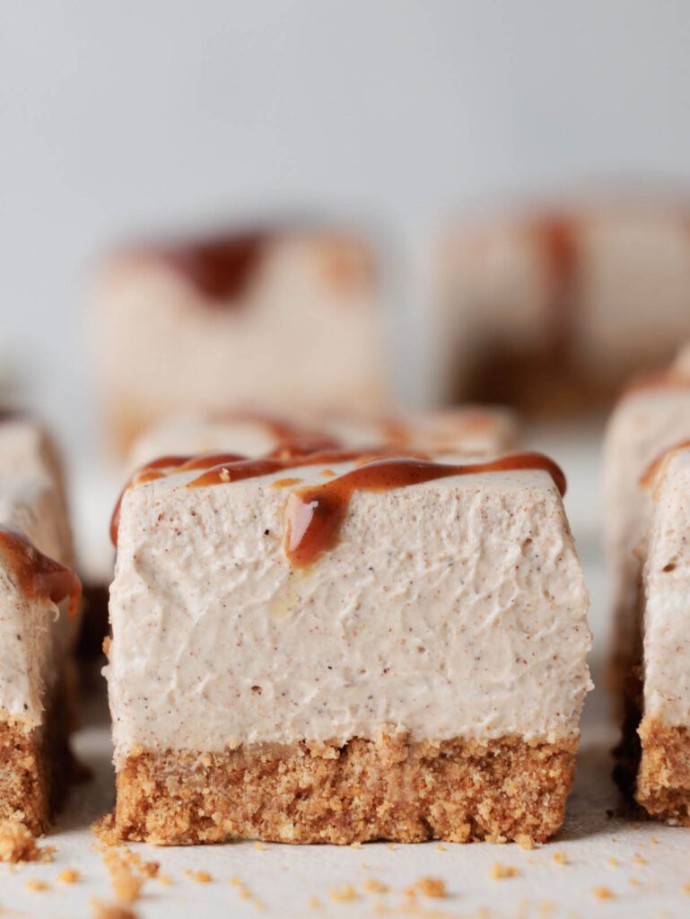 Sideview of sliced cheesecake with caramel drizzle on top.