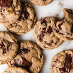 Cookies scattered on marble with chocolate on top.