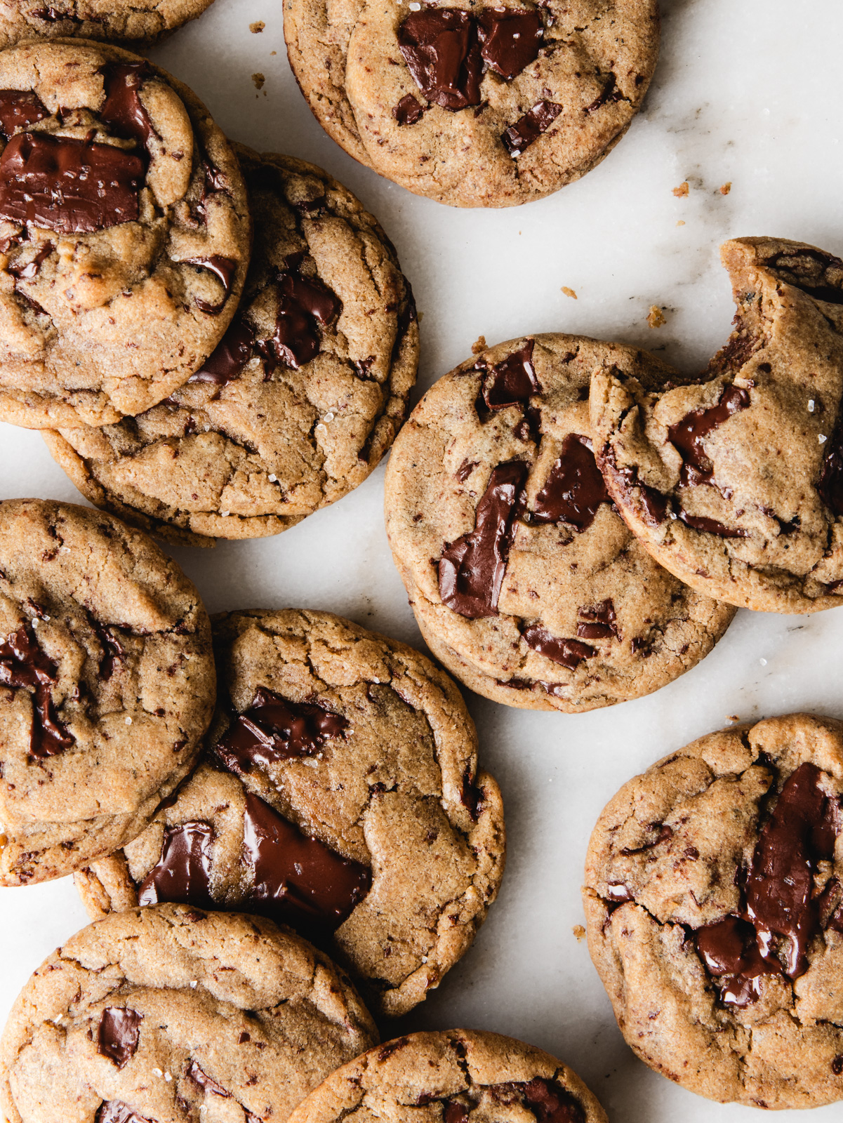 Cookies scattered on marble with chocolate on top.