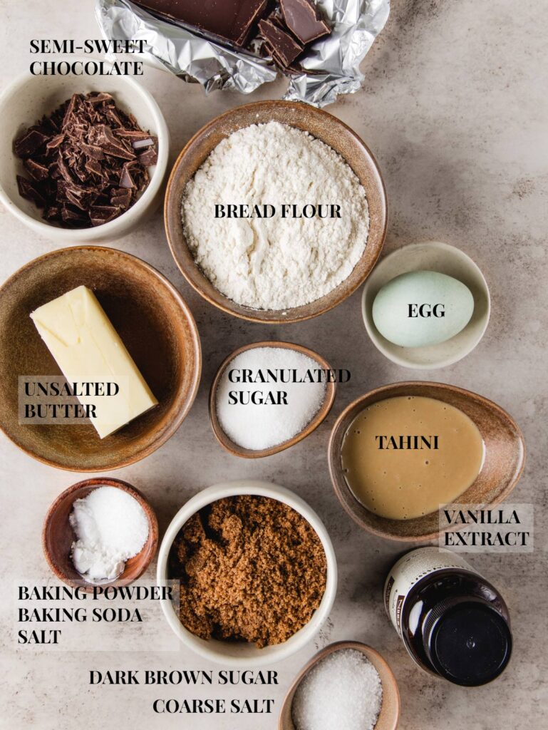 Ingredients for chocolate chip tahini cookies in bowls with labels.